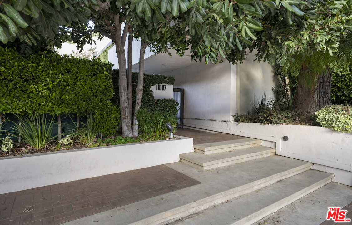 11687 Bellagio Road, Unit 3 Los Angeles, CA 90049 - Photo 29 of 31 a front view of a house with garden and trees