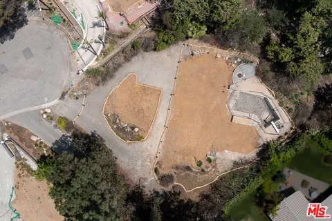 an aerial view of a house with a yard and trees all around