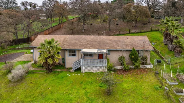 an aerial view of a house with yard and trees