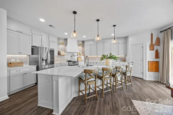 a kitchen with stainless steel appliances a dining table chairs stove and white cabinets