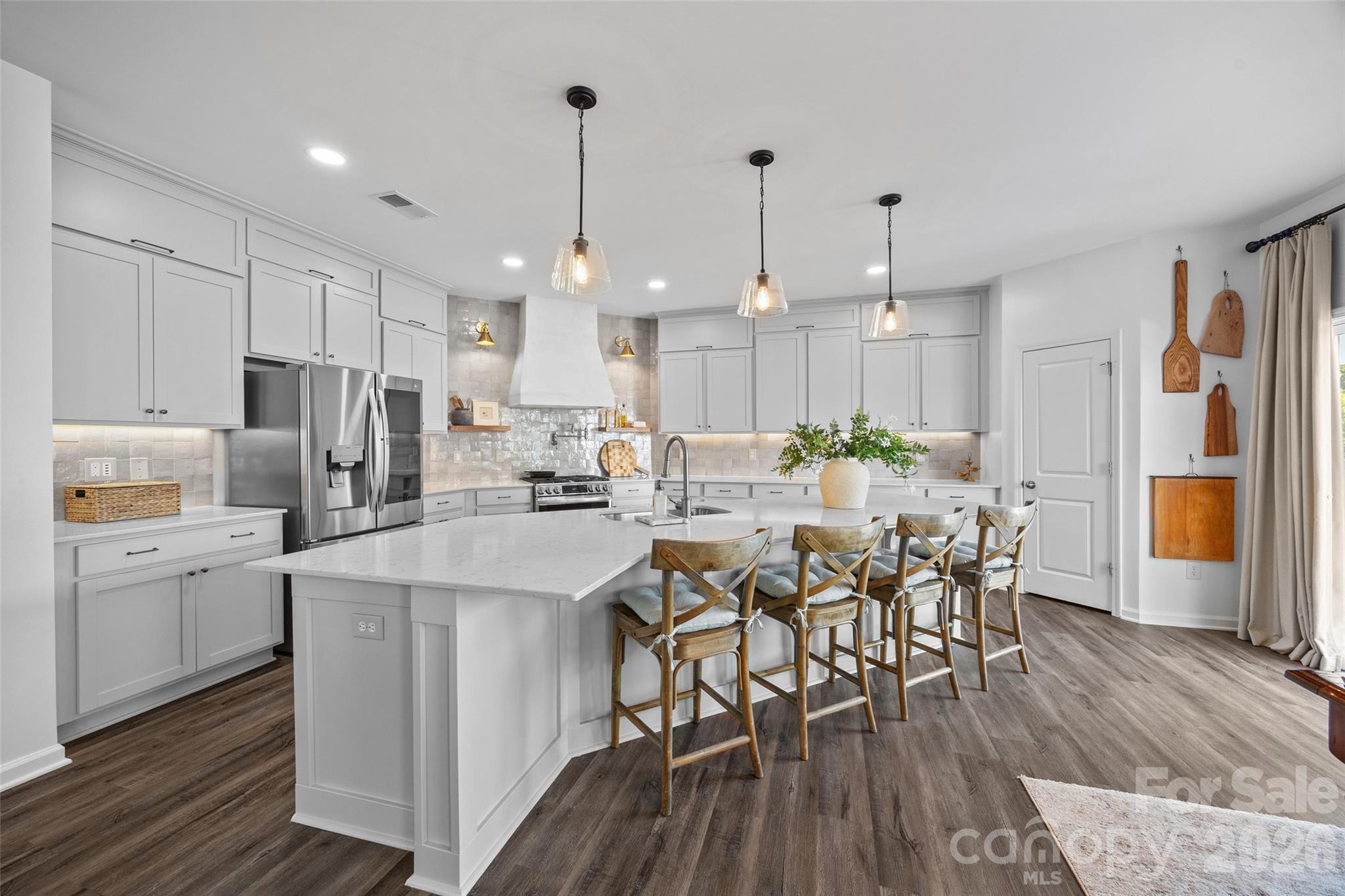 a kitchen with stainless steel appliances a dining table chairs stove and white cabinets