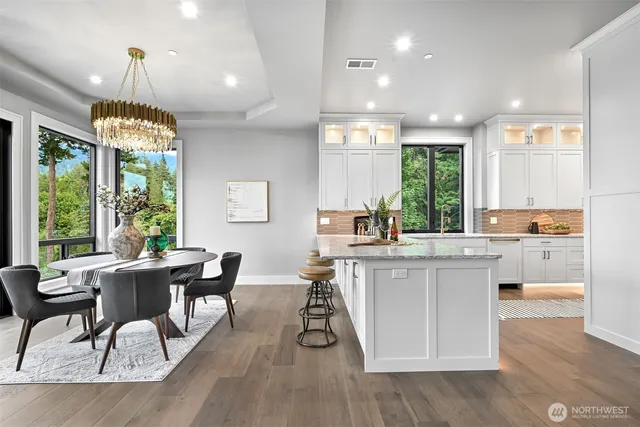 a kitchen with stainless steel appliances granite countertop a stove top oven a dining table and chairs with wooden floor