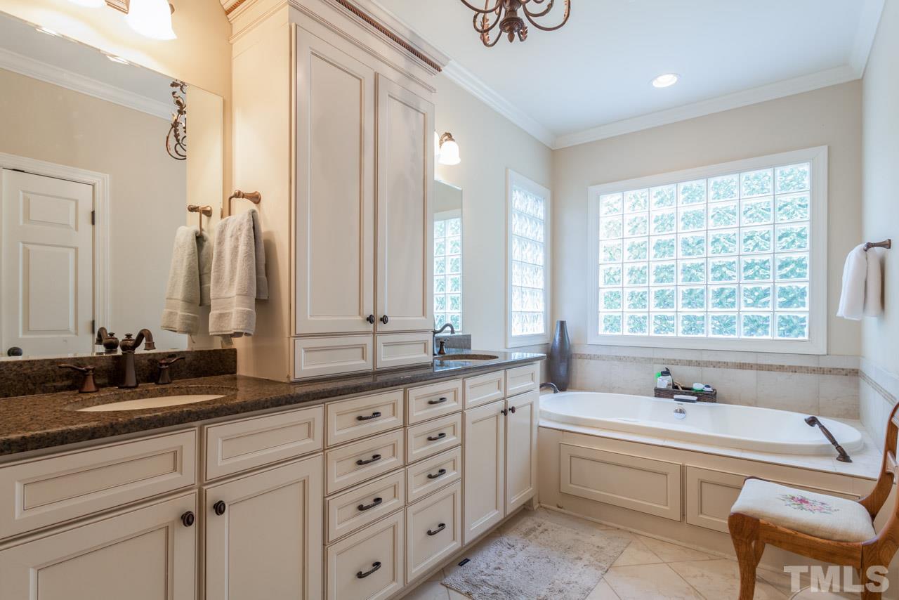 2425 Coley Forest Place Raleigh, NC 27612 - Photo 12 of 24 a bathroom with double vanity sinks a large mirror and a bathtub