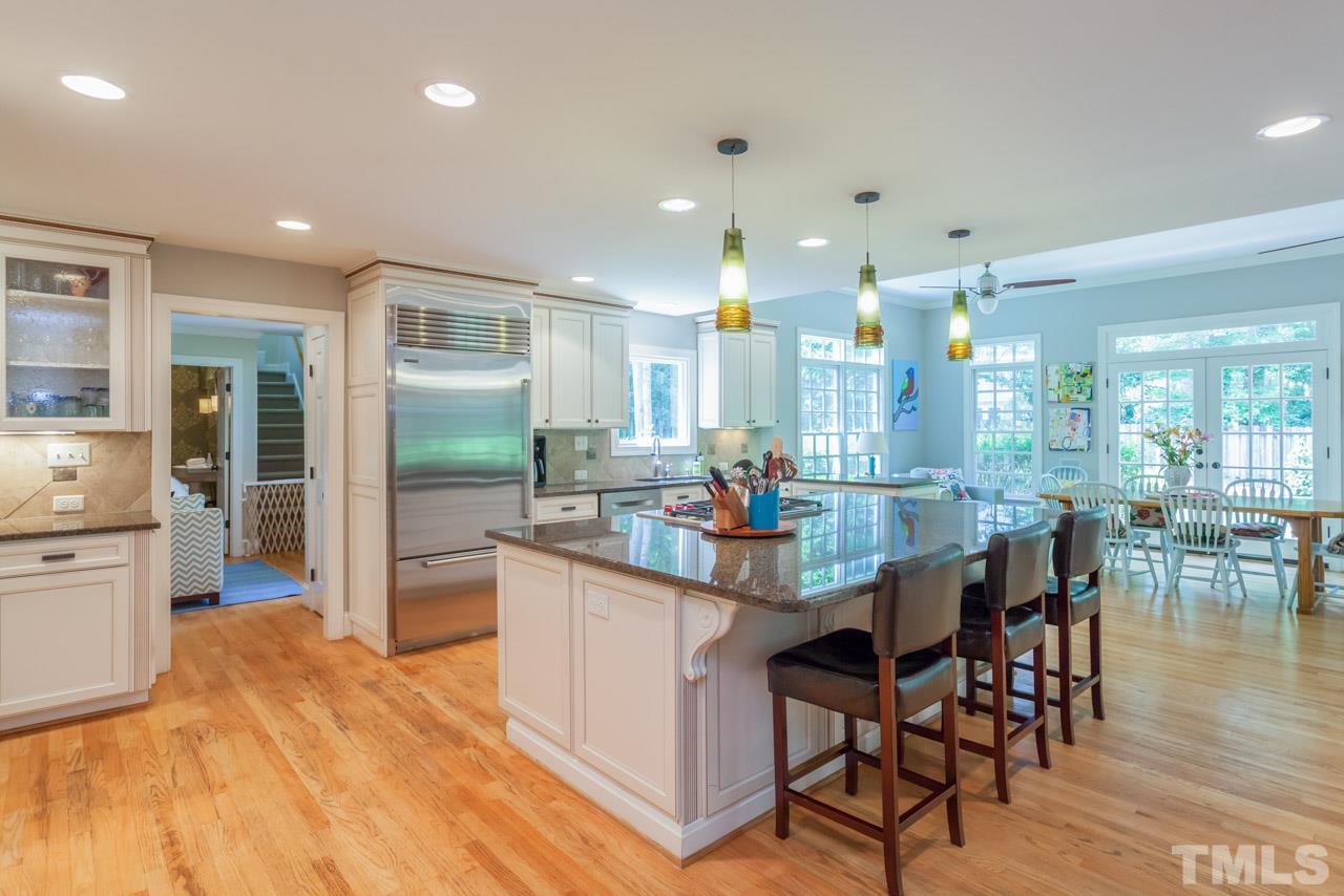 2425 Coley Forest Place Raleigh, NC 27612 - Photo 3 of 24 a kitchen with stainless steel appliances kitchen island granite countertop a table chairs sink and wooden cabinets