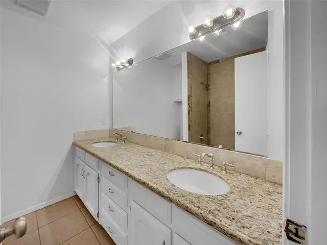 a bathroom with a granite countertop double vanity sink and a mirror