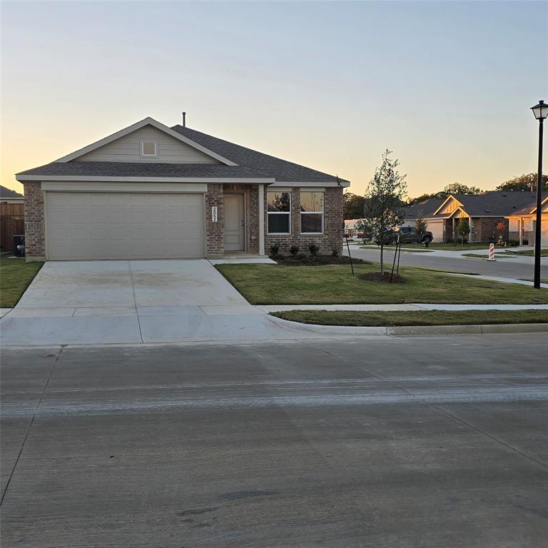 Ranch-style house with roof with shingles, brick siding, concrete driveway, and a front yard