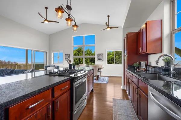 a kitchen with kitchen island granite countertop a sink stove and cabinets