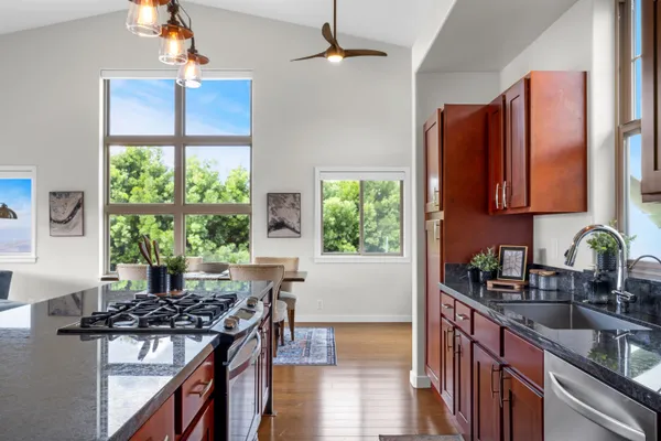 a kitchen with stainless steel appliances granite countertop a stove a sink dishwasher and a refrigerator with wooden floor