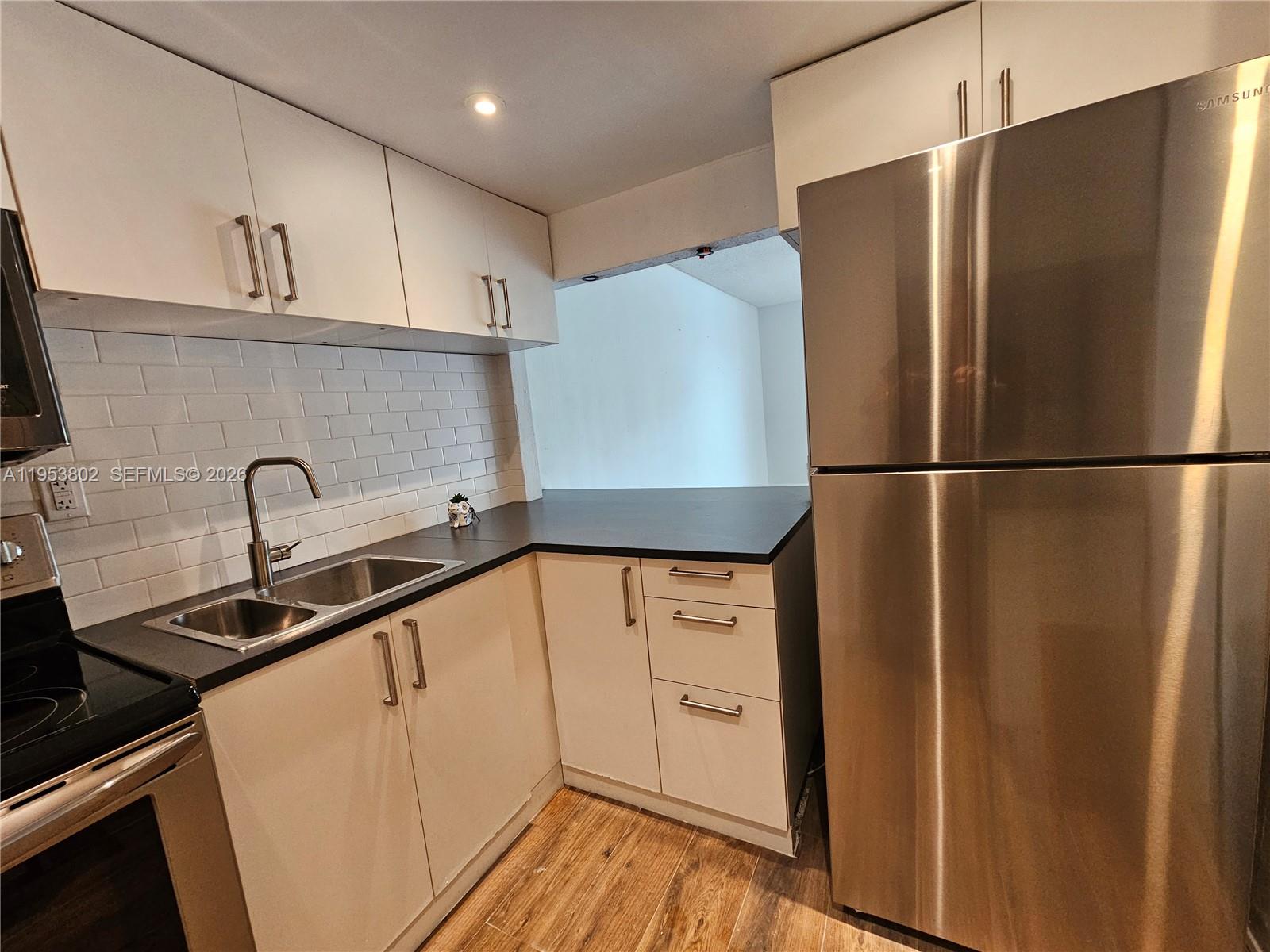 4550 Northwest 9th Street, Unit 315E Miami, FL 33126 - Photo 3 of 15 a kitchen with stainless steel appliances a refrigerator sink and cabinets