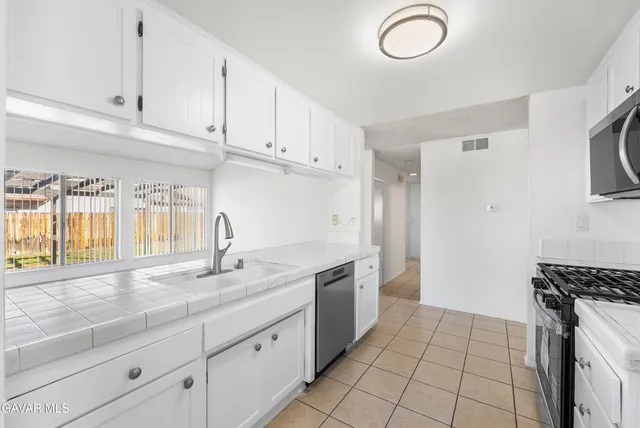 a kitchen with granite countertop a stove a sink and a white cabinets