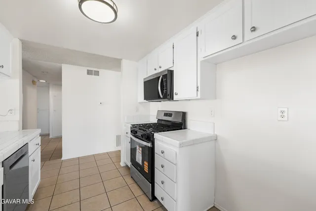 a large kitchen with stainless steel appliances granite countertop a sink stove and microwave