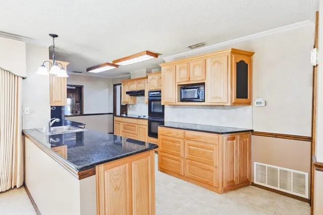 a kitchen with stainless steel appliances granite countertop a sink and a refrigerator