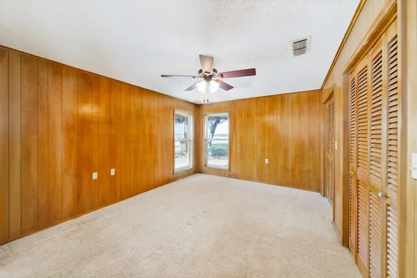 a view of a big room with windows and chandelier fan