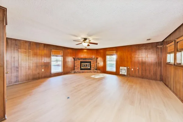 a view of an empty room with window and wooden floor