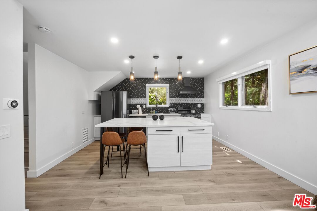 23400 West Moon Shadows Drive Malibu, CA 90265 - Photo 24 of 31 a large white kitchen with wooden floor and a fireplace