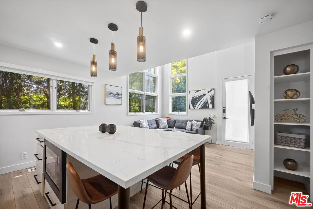 23400 West Moon Shadows Drive Malibu, CA 90265 - Photo 25 of 31 a kitchen with stainless steel appliances a dining table chairs and wooden floor