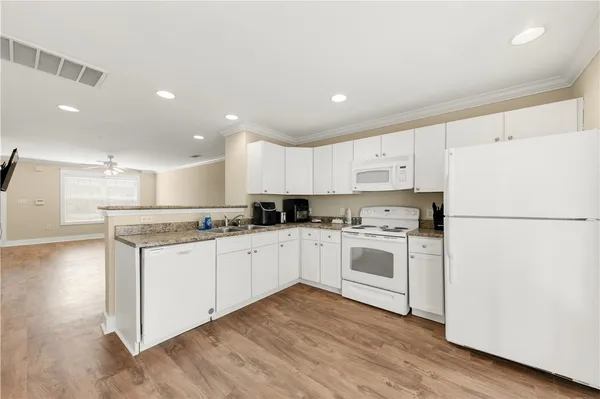 a kitchen with granite countertop white cabinets and white appliances