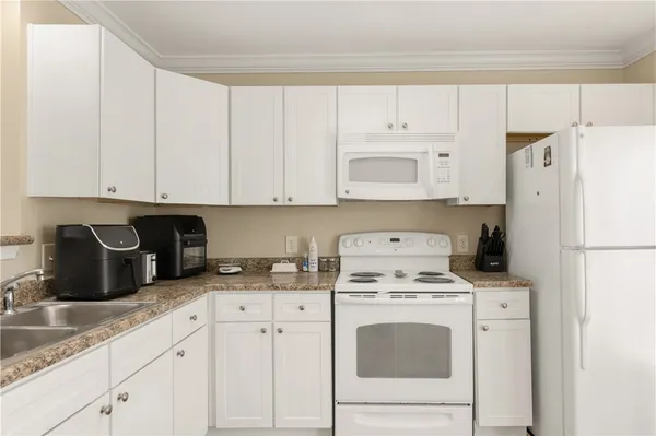a kitchen with granite countertop white cabinets and white appliances