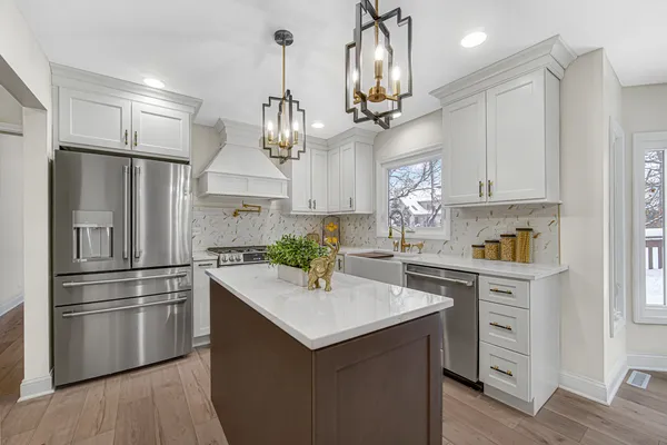 a kitchen with kitchen island white cabinets and stainless steel appliances