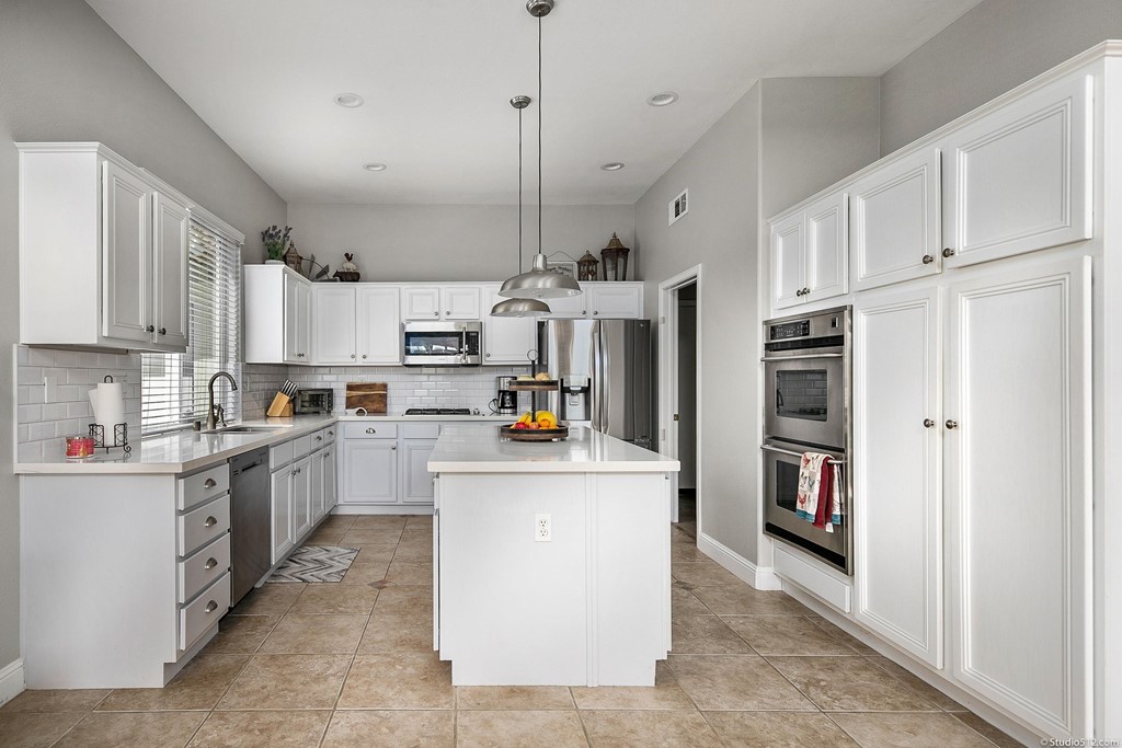 811 Inverlochy Drive Fallbrook, CA 92028 - Photo 5 of 27 a kitchen with stainless steel appliances kitchen island granite countertop a refrigerator oven a sink a stove and white cabinets