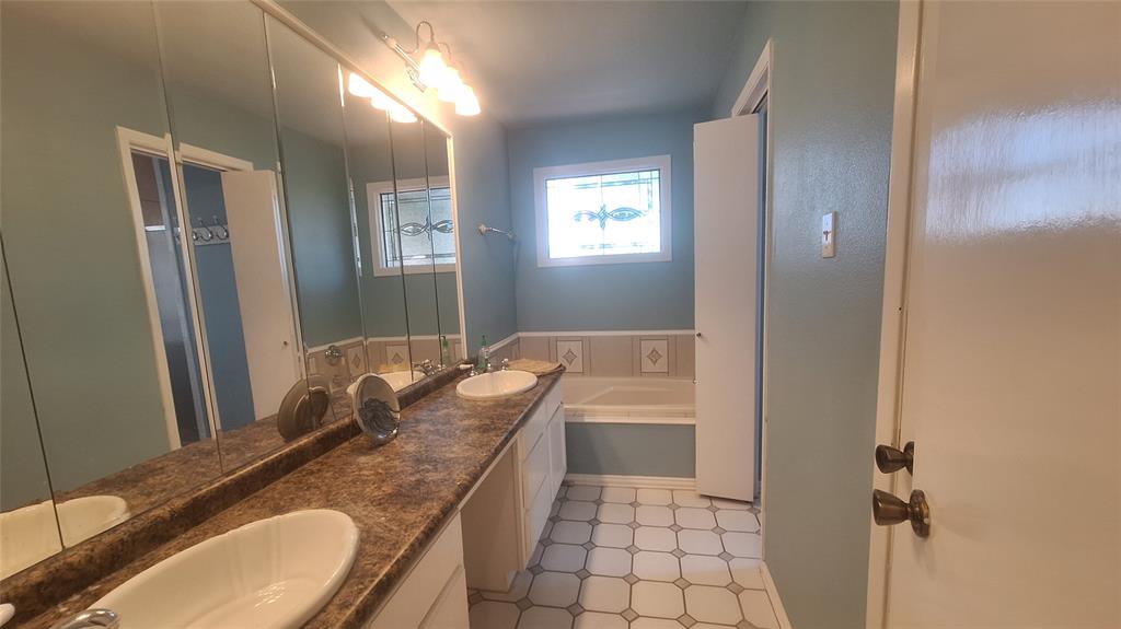 613 Colts Neck Court Colleyville, TX 76034 - Photo 13 of 38 master bath with long makeup vanity separated by 2 sinks, jet tub with stain glass accent window above & 2nd WI closet
