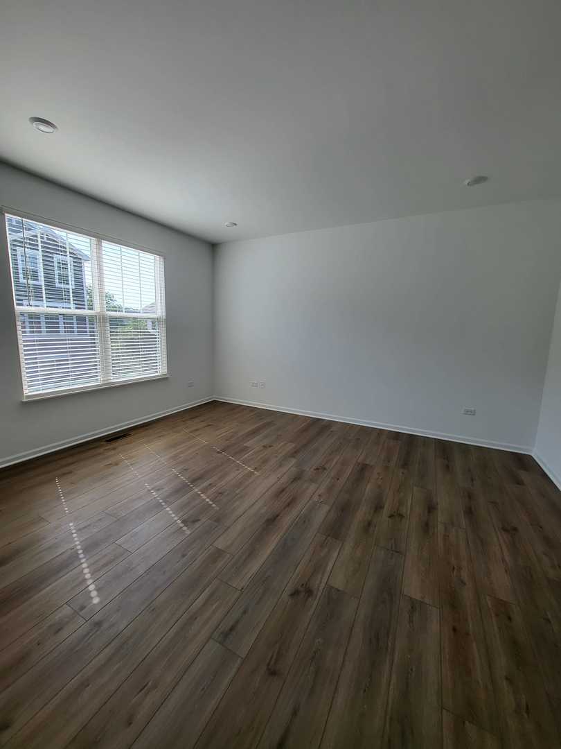 588 Wolverine Drive Aurora, IL 60502 - Photo 5 of 29 an empty room with wooden floor and windows