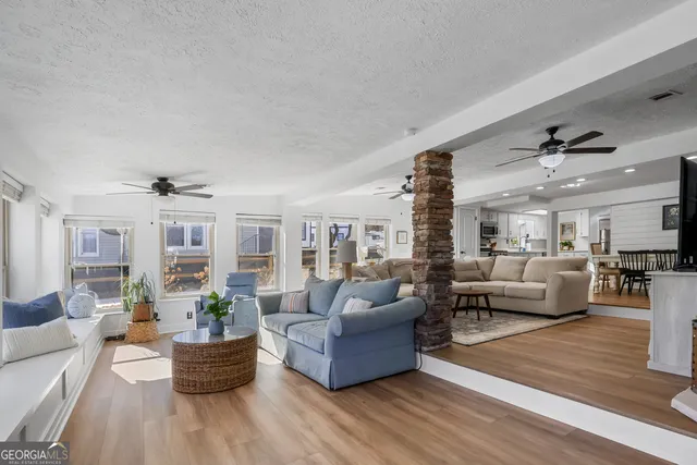 a living room with furniture large windows and wooden floor
