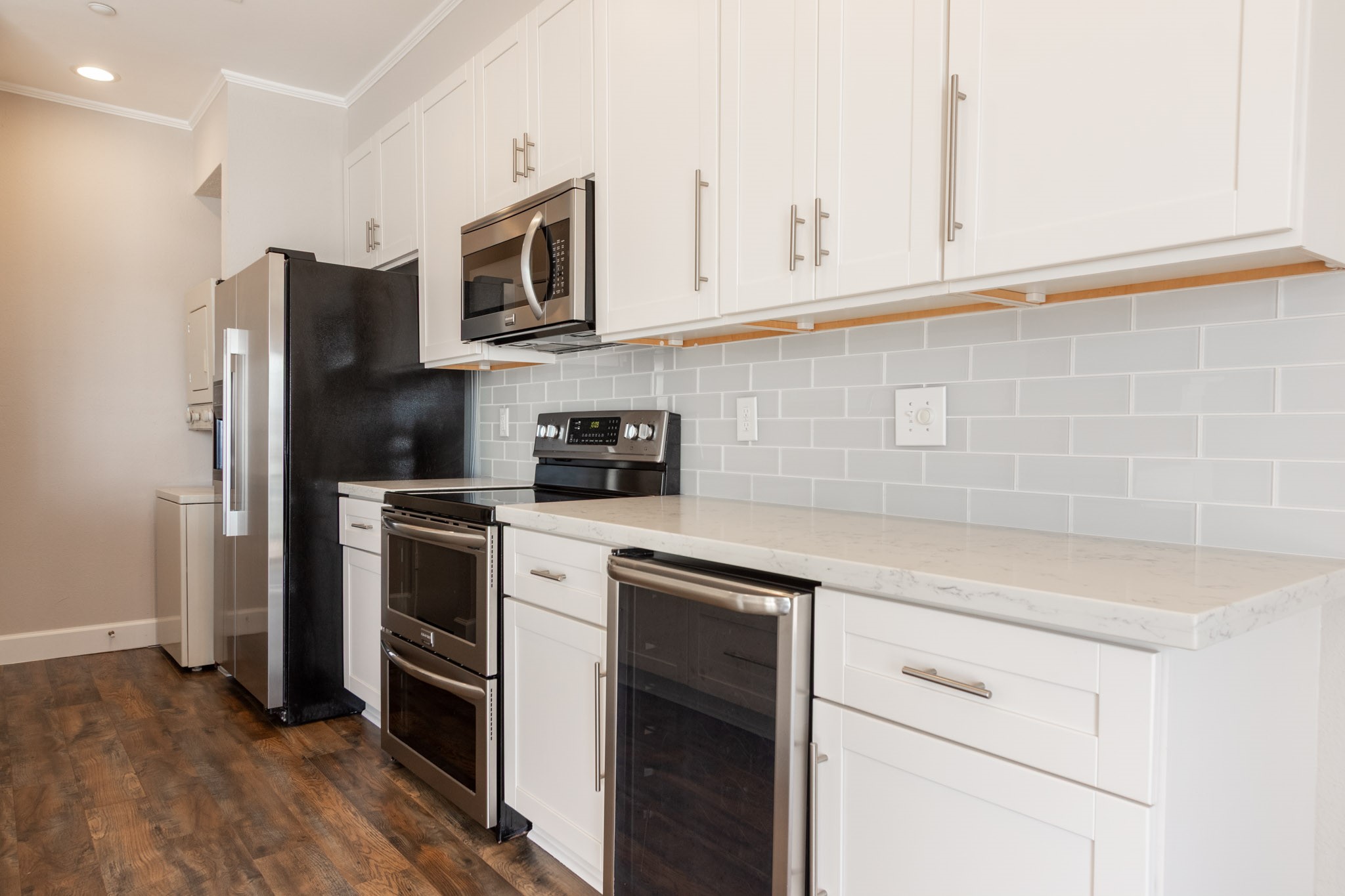 401 Lakeside Lane, Unit 111 Nassau Bay, TX 77058 - Photo 11 of 45 a kitchen with stainless steel appliances white cabinets and a stove a refrigerator with wooden floor