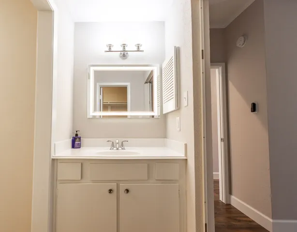 a bathroom with a granite countertop sink a mirror a vanity and shower