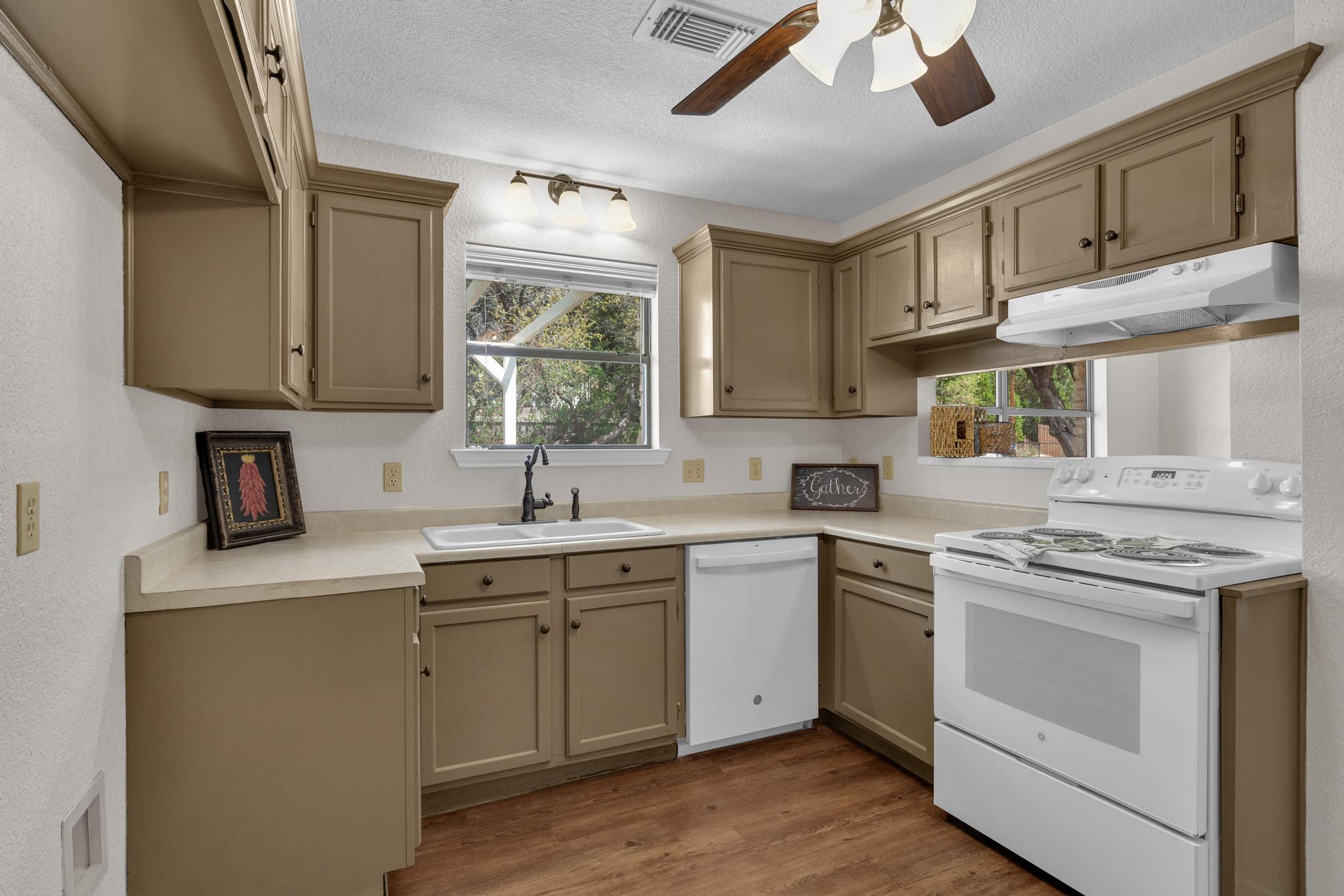 7902 Bar K Ranch Road Lago Vista, TX 78645 - Photo 12 of 35 Kitchen featuring white appliances, ceiling fan, light wood finished floors, light countertops, and a textured wall