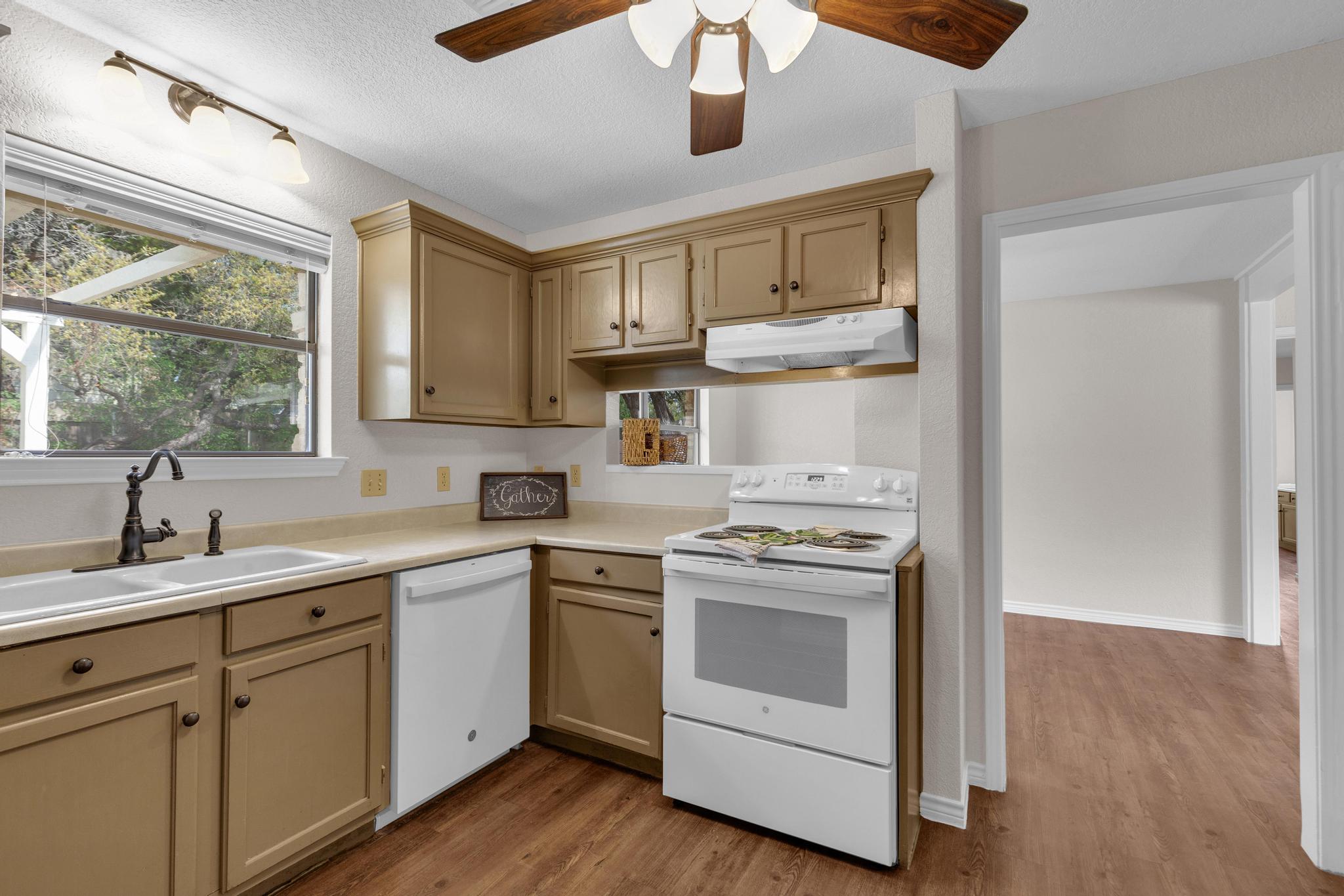 7902 Bar K Ranch Road Lago Vista, TX 78645 - Photo 13 of 35 Kitchen with white appliances, ceiling fan, dark wood-style flooring, and light countertops