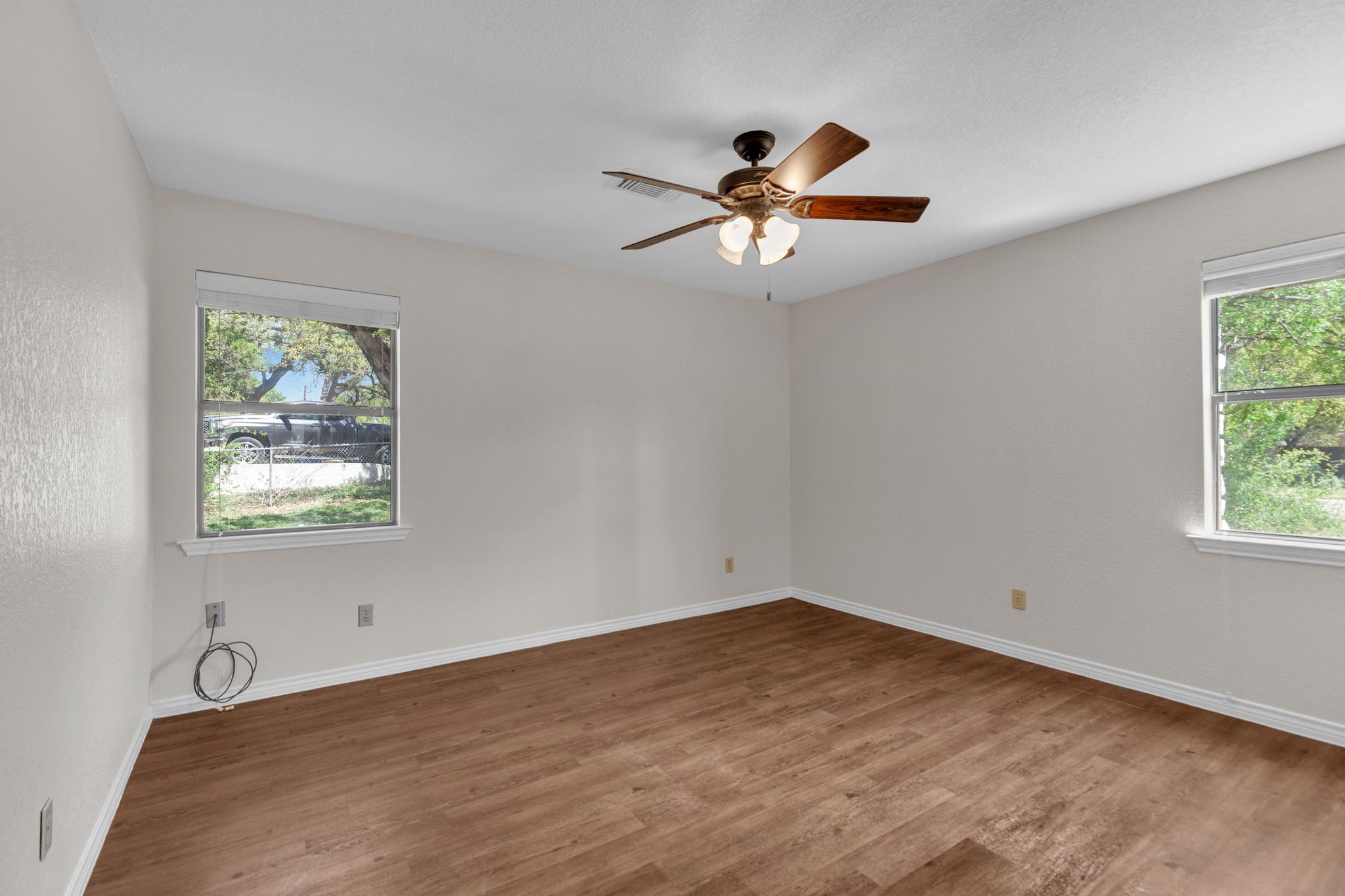 7902 Bar K Ranch Road Lago Vista, TX 78645 - Photo 19 of 35 Empty room featuring dark wood finished floors, plenty of natural light, and a ceiling fan