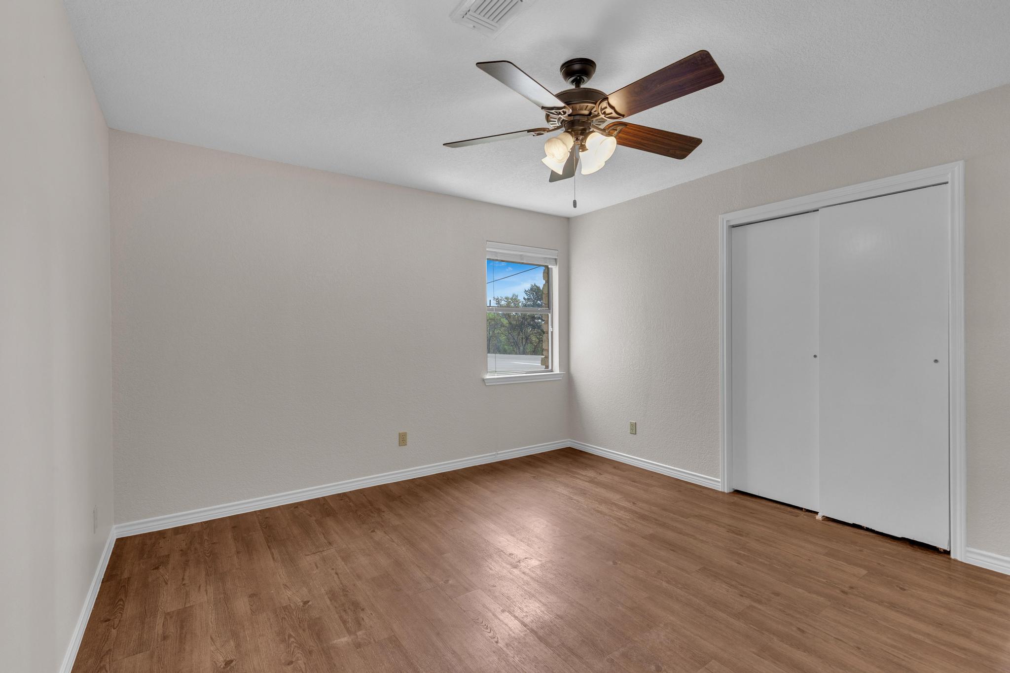 7902 Bar K Ranch Road Lago Vista, TX 78645 - Photo 21 of 35 Unfurnished bedroom with wood finished floors, a closet, and ceiling fan