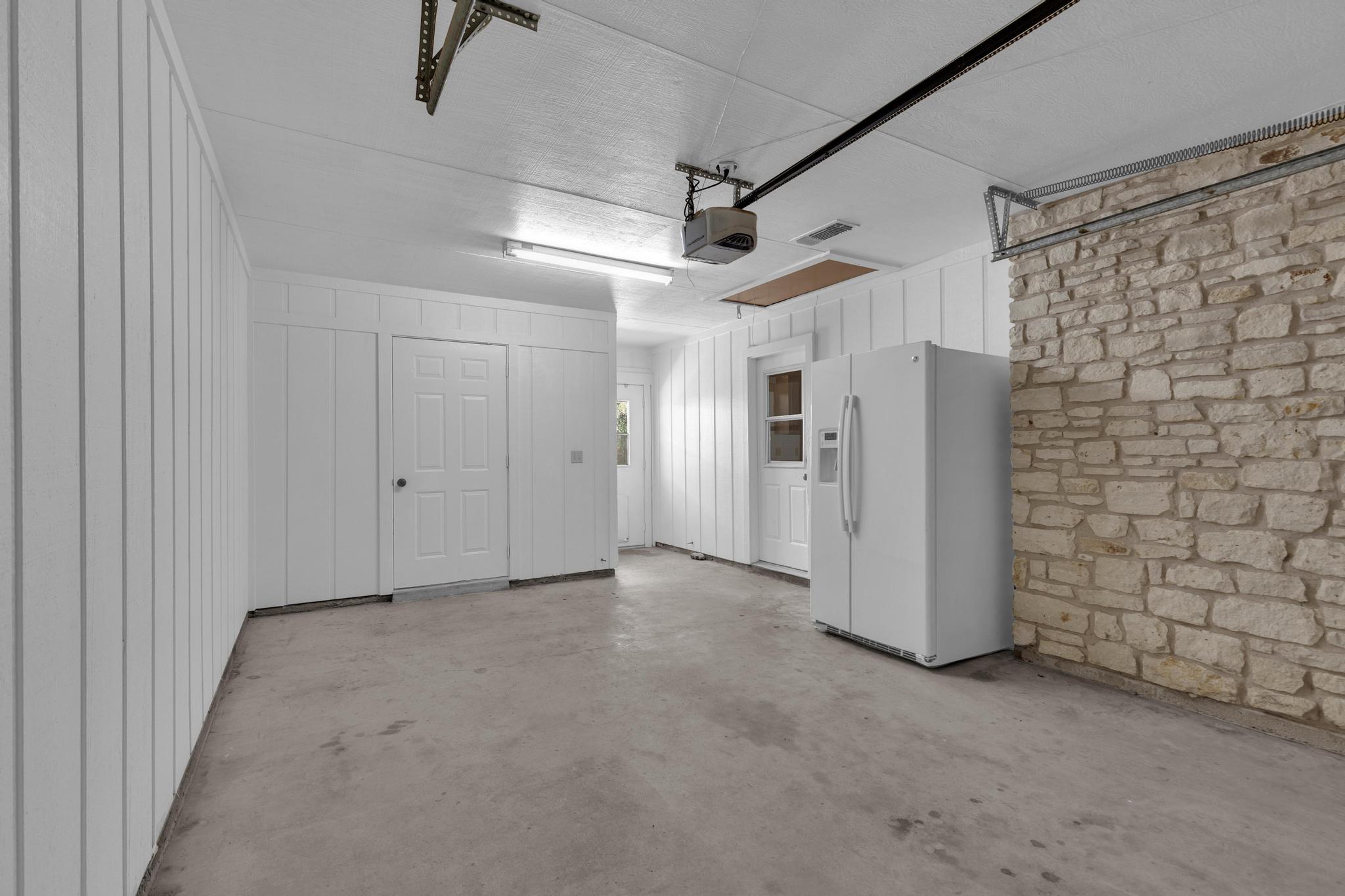 7902 Bar K Ranch Road Lago Vista, TX 78645 - Photo 25 of 35 Garage with white fridge with ice dispenser and a garage door opener