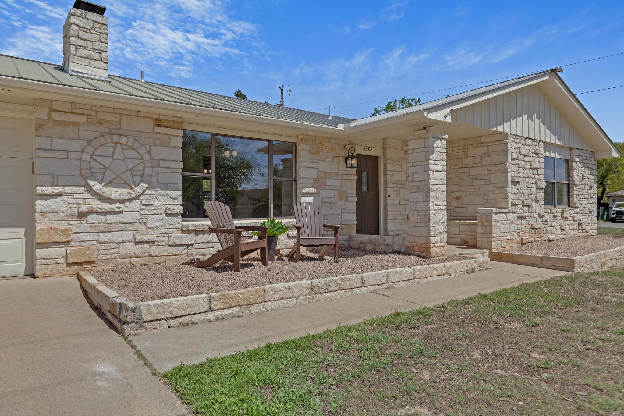 7902 Bar K Ranch Road Lago Vista, TX 78645 - Photo 27 of 35 View of exterior entry with stone siding, a chimney, and board and batten siding