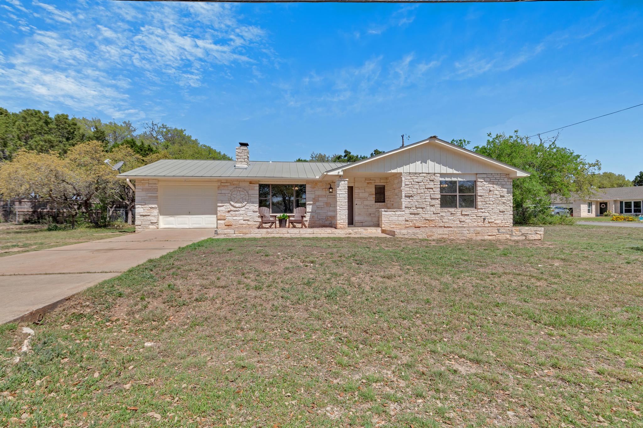 7902 Bar K Ranch Road Lago Vista, TX 78645 - Photo 29 of 35 Ranch-style home featuring a garage, a front lawn, concrete driveway, and a chimney