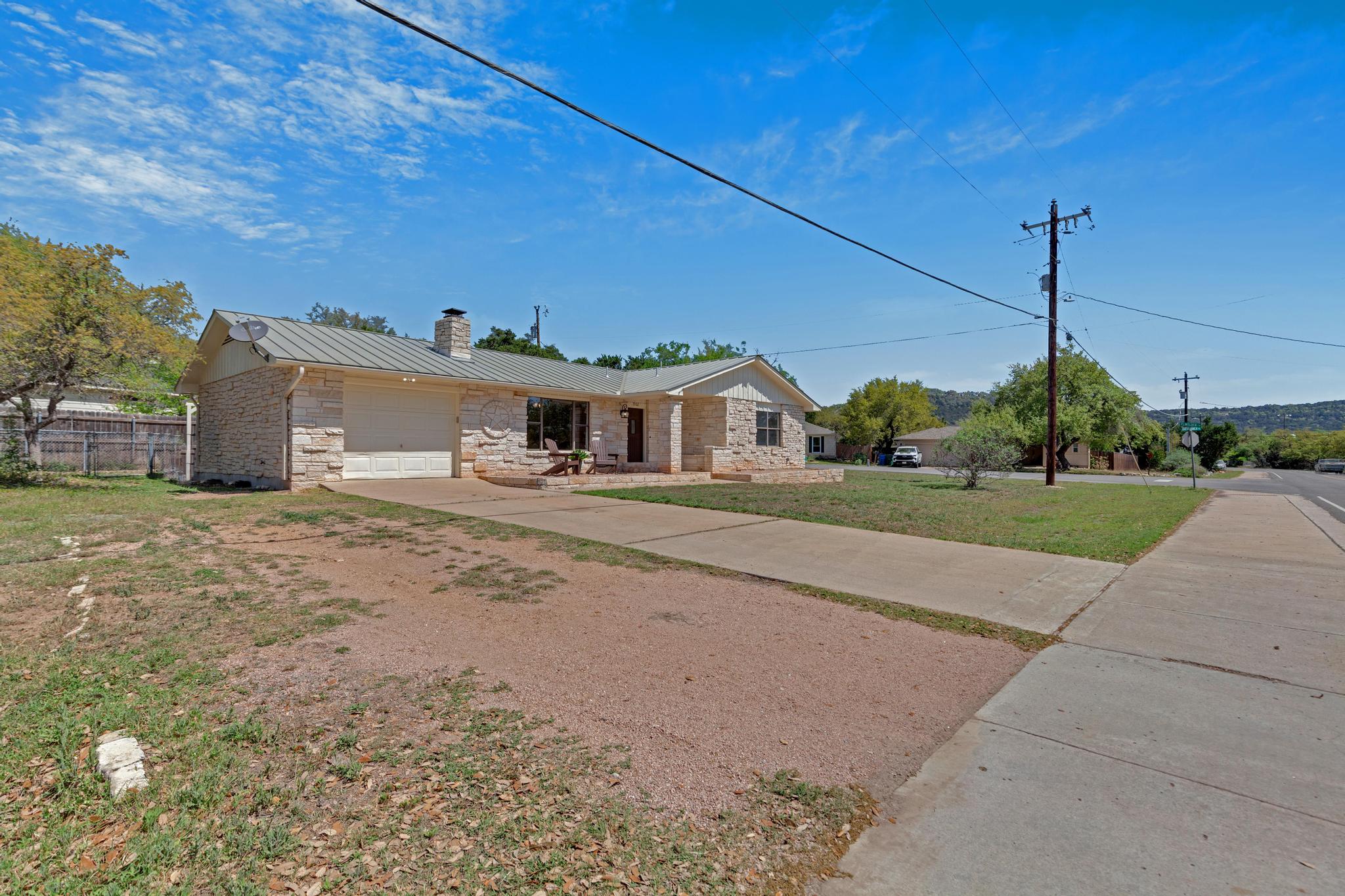 7902 Bar K Ranch Road Lago Vista, TX 78645 - Photo 31 of 35 Ranch-style home with an attached garage, concrete driveway, a chimney, and a standing seam roof