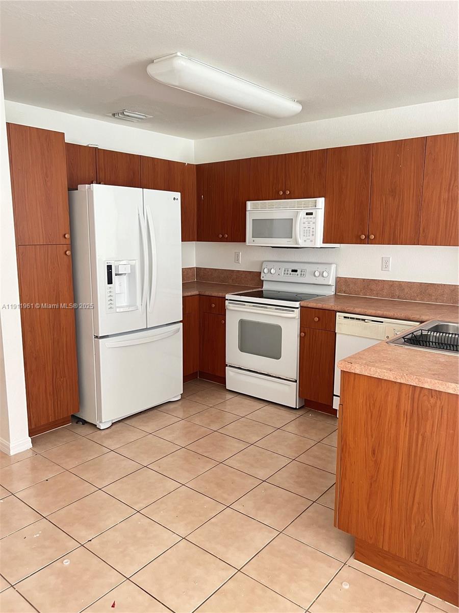 12906 Southwest 30th Street, Unit 134 Miramar, FL 33027 - Photo 5 of 13 a kitchen with stainless steel appliances granite countertop a stove a refrigerator and a cabinets