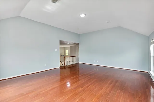 an empty room with wooden floor chandelier fan and windows