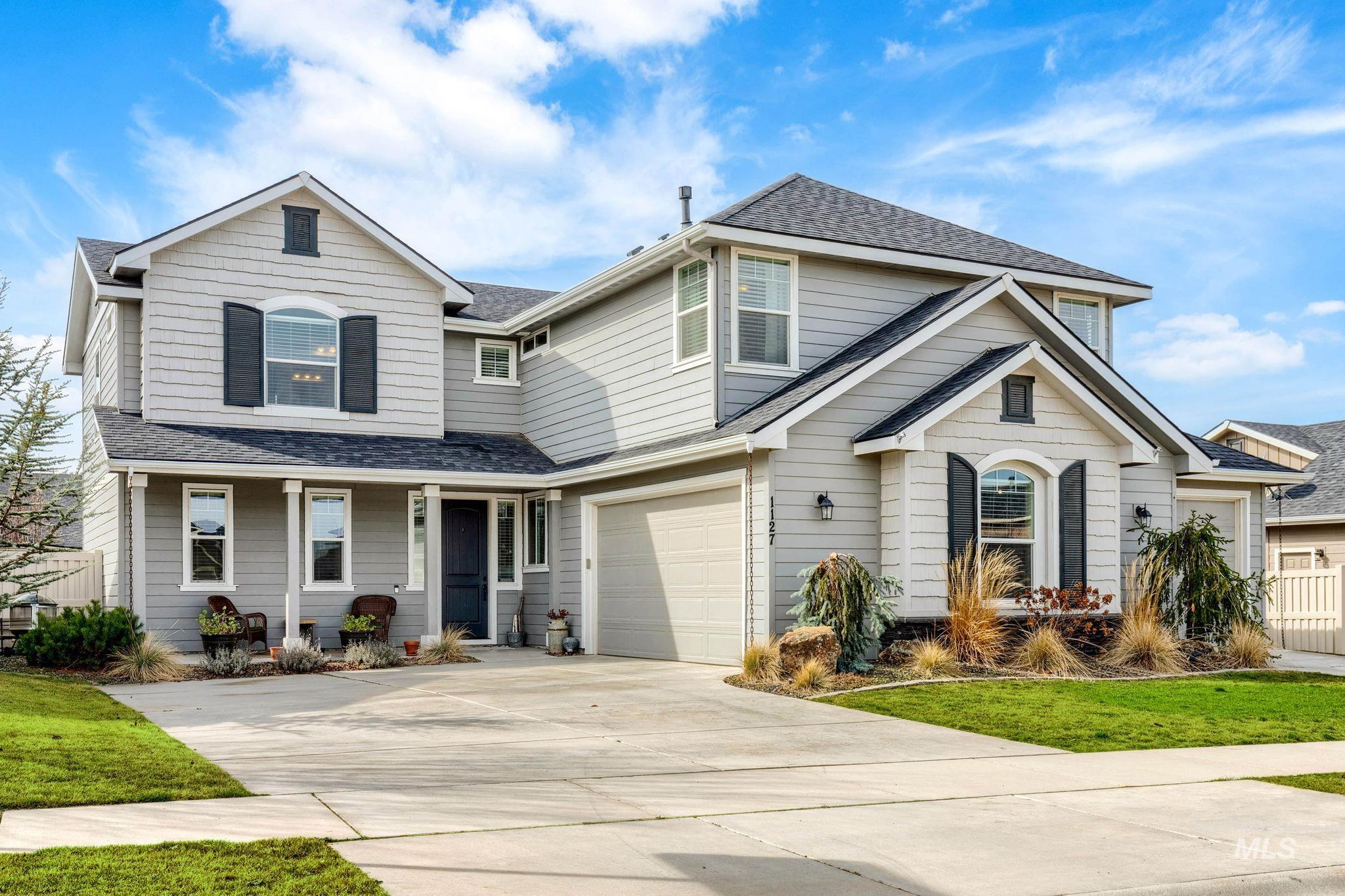 View of front of property with roof with shingles, concrete driveway, and a covered porch