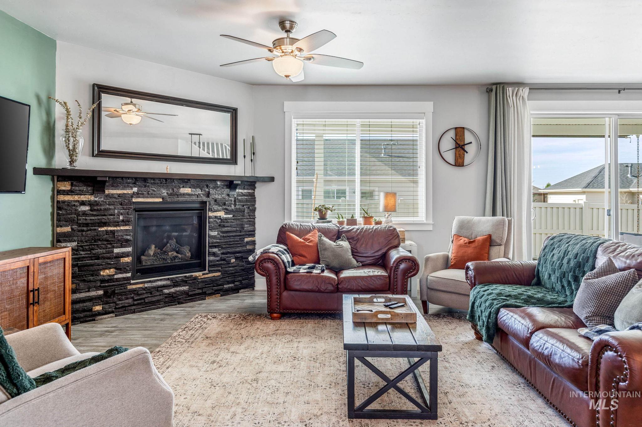 1127 Overland Trail Street Middleton, ID 83644 - Photo 3 of 24 Living room featuring a stone fireplace, large windows wood finished floors, and ceiling fan
