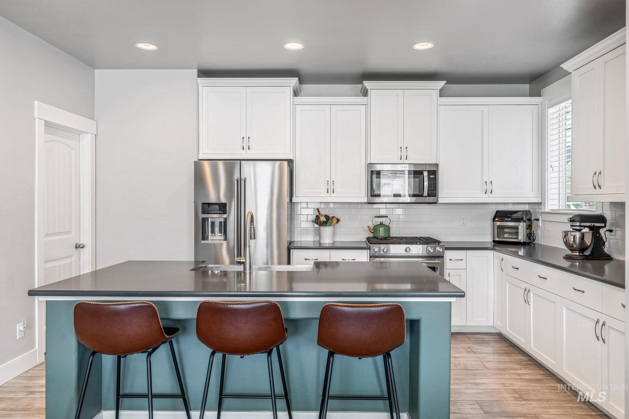 1127 Overland Trail Street Middleton, ID 83644 - Photo 5 of 24 Kitchen with high end appliances, a breakfast bar, white cabinets, recessed lighting, and a center island with bib front sink