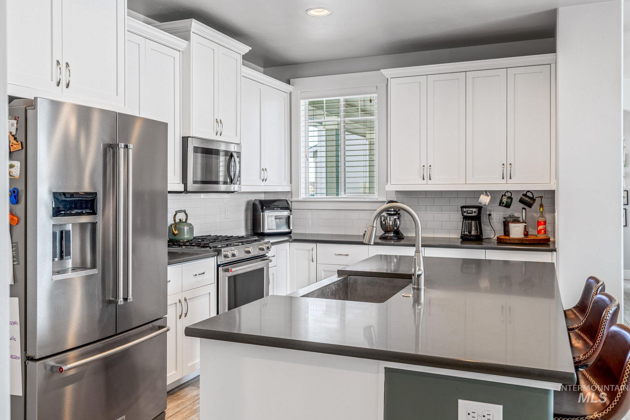 1127 Overland Trail Street Middleton, ID 83644 - Photo 6 of 24 Kitchen with stainless steel appliances, white cabinets, decorative backsplash, light wood-type flooring, and recessed lighting