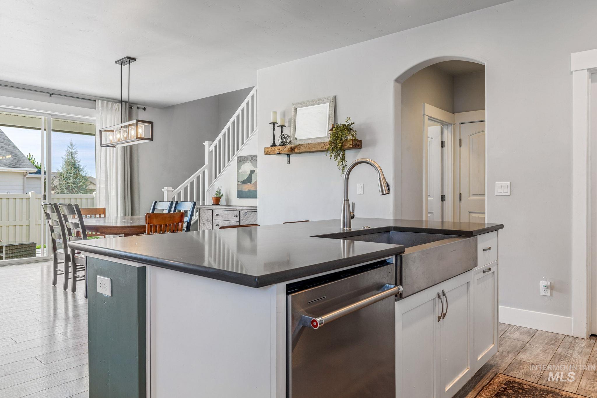 1127 Overland Trail Street Middleton, ID 83644 - Photo 8 of 24 Kitchen with a kitchen island with sink, stainless steel dishwasher, white cabinets, light wood-type flooring, and decorative light fixtures