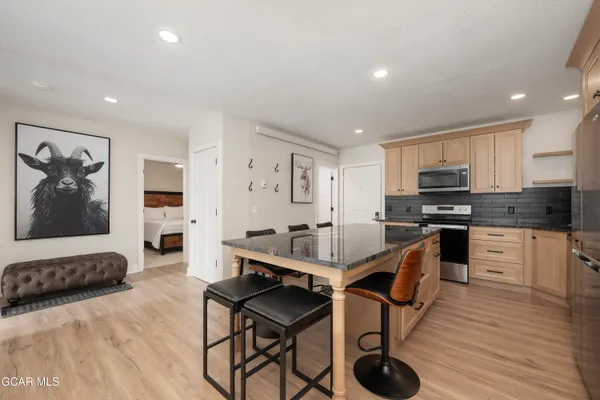 a kitchen with granite countertop a stove a refrigerator and wooden floor