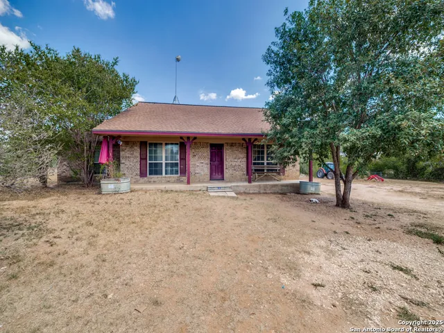 a view of a house with floor to ceiling window and a large tree