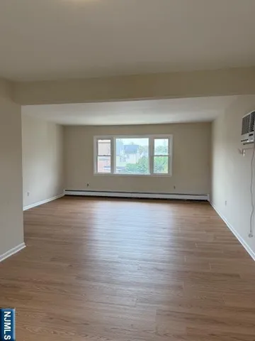 a view of empty room with window and wooden floor