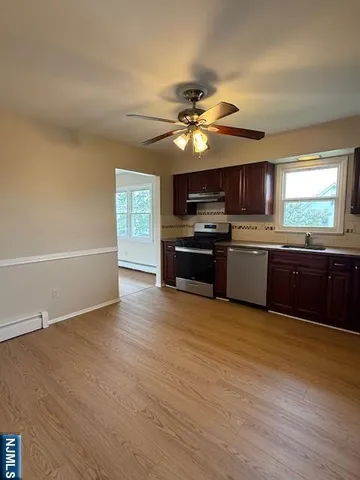 a view of kitchen with granite countertop cabinets stainless steel appliances and a flat screen tv