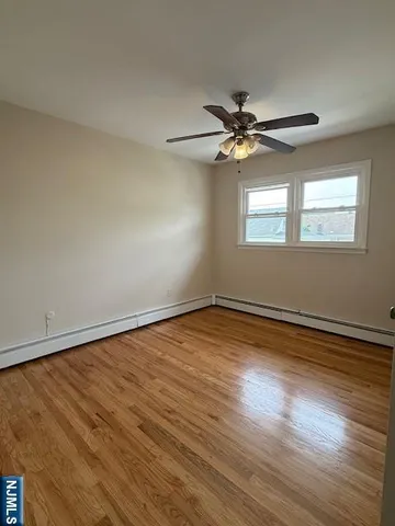 an empty room with wooden floor fan and windows