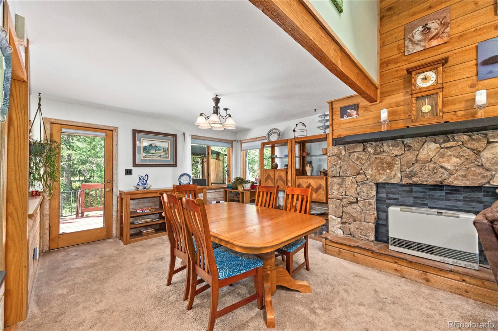 444 Nova Road Pine, CO 80470 - Photo 14 of 40 a dining room with furniture a fireplace and a chandelier